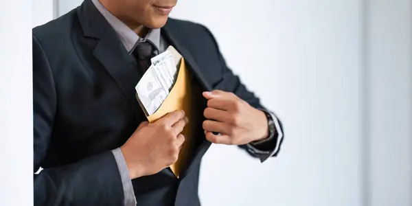 Businessman briefcase document envelope with dollar banknotes on white background. businessman putting illegal secret agreement money in his jacket. corruption, bribery, crime and embezzle concept.