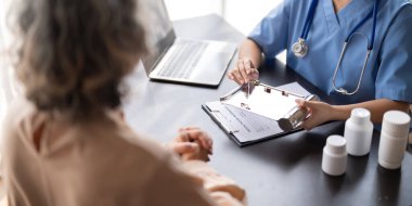 Doktor ya da doktor yaşlı kadın hastaya ilaç reçetesi öneriyor.