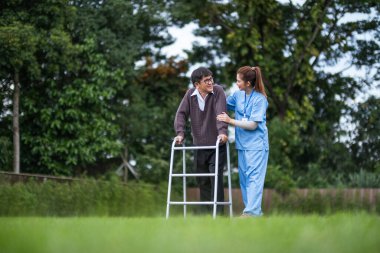 Fizyoterapist, yaşlı bir adamla evde yürüteç kullanarak konuşuyor. konsept evde sağlık hemşiresi, evde yaşlı bir yetişkinle fizik tedavi.