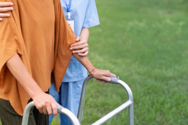 Hemşire ya da bakıcı destek, yardım ya da rehabilitasyonda hareket eden bacağa güvenmek için yürüme iskeletinde el ele tutuşur. Fizyoterapi sağlık hizmetleri, tıbbi bakım danışmanlığı evde engelli yaşlı bir hasta.