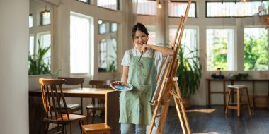 Güzel Asyalı yaratıcı kadın ressam resim stüdyosunda kendine güvenen bir resim yapıyor..