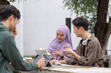 Çok ırklı sınıf arkadaşlarıyla birlikte kampüs parkında oturan öğrenci arkadaşlığı kavramı. Milenyum insanları dışarıda eğleniyor. Gençlik ve eğitim.