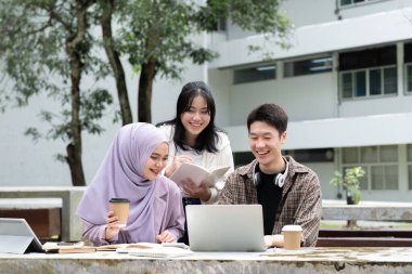 Çok ırklı sınıf arkadaşlarıyla birlikte kampüs parkında oturan öğrenci arkadaşlığı kavramı. Milenyum insanları dışarıda eğleniyor. Gençlik ve eğitim.