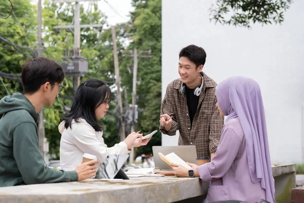 Çok ırklı sınıf arkadaşlarıyla birlikte kampüs parkında oturan öğrenci arkadaşlığı kavramı. Milenyum insanları dışarıda eğleniyor. Gençlik ve eğitim.