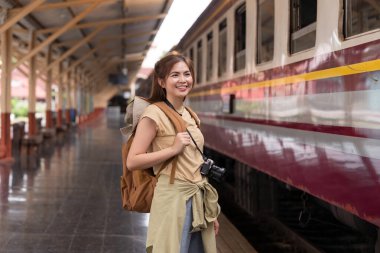 Sırt çantalı güzel Asyalı gezgin tren istasyonunda trene biniyor..