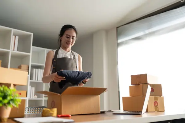 Young woman working online ecommerce shopping at her shop. Young woman seller prepare parcel box of product for deliver to customer. Online selling, ecommerce. Selling products online.
