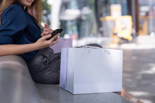 Kara Cuma Akıllı Telefon Kullanan Bir Kadın Alışveriş Merkezinde Otururken — Stok fotoğraf