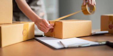 Asyalı kadın, paketleme, nakliye, çevrimiçi satış İnternet pazarlama ekommerce konsepti başlangıç iş fikri için paket kutuları eklemek için koli bandı kullanıyor.