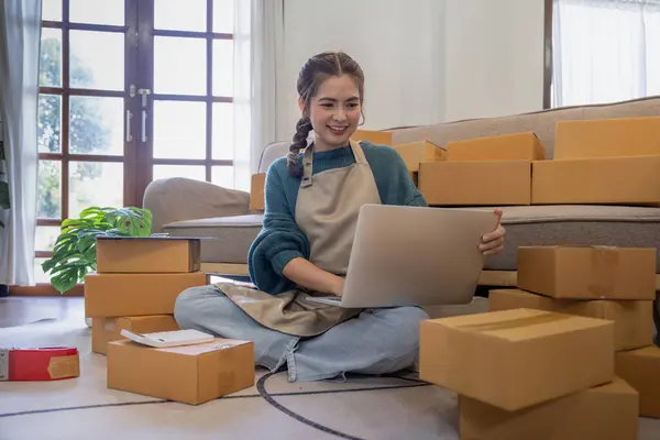 Young woman working online ecommerce shopping at her shop. Young woman seller prepare parcel box of product for deliver to customer. Online selling, ecommerce. Selling products online.