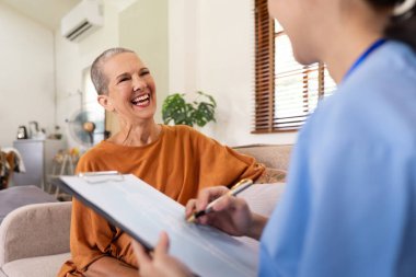 Asyalı genç kadın bakıcı doktor ev ziyareti sırasında yaşlı kadın hastalara danışma ve yazma sorunu veriyor.