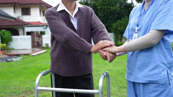 Nurse or caregiver hand on walking frame for support, help or trust moving leg in rehabilitation. Physiotherapy healthcare, Medical caregiver consulting disabled elderly patient at home.