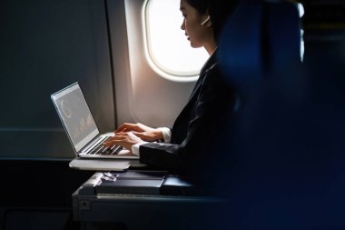 Başarılı Asyalı iş kadını, uçuş sırasında laptopta çalışan iş kadını..