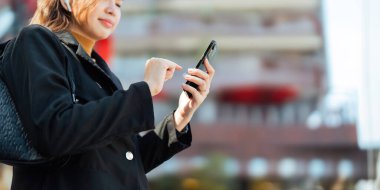 Başarılı bir iş kadını açık havada gezer. Güzel bir kadın akıllı telefonuyla işe gidiyor. Ofis binasının yanında yürüyor..