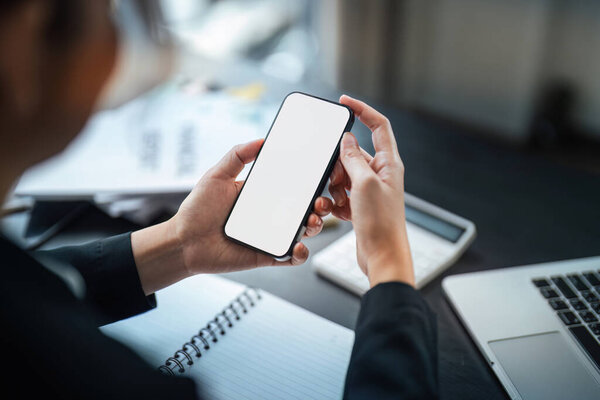 Business woman hand holding using mockup mobile phone with white blank screen for text, mobile app design and advertising, online marketing.