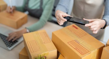 Küçük işletme KOBİ sahibi, iki genç Asyalı iş sahibi kadın paket kutusu hazırlıyor ve çevrimiçi ürün siparişlerini müşteri, ambalaj, Alışveriş Online konseptine göndermek için kontrol ediyor.