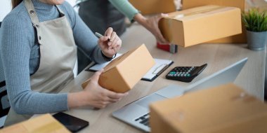 İş yerinde bilgisayarla çalışan küçük bir işletme sahibi. İki kadın satıcı ürün siparişini kontrol ediyor. Müşteriye teslimat için mal paketliyorum. Çevrimiçi satış. Ticaret için. Çevrimiçi Alışveriş.