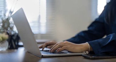 Evinde dizüstü bilgisayarla çalışan profesyonel bir iş kadını, masa başında otururken bilgisayar kullanan genç bir bayan yönetici, iş süreci konsepti.