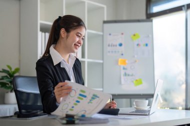 Çekici Asyalı iş kadını ofiste dizüstü bilgisayarla çalışıyor..