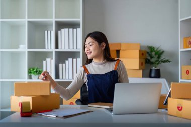 Kadınlar paketleme, nakliyat, çevrimiçi satış, internet pazarlama ekommerce konsepti girişimi fikrine ürün hazırlamak için koli bandı kullanırlar..