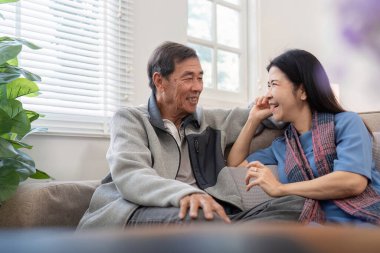 Mutlu olgun karı koca oturma odasında rahat bir koltuğa oturur sohbet eder, yaşlı çiftin keyfine bakar kanepede dinlenir sohbet eder hafta sonlarında güler eğleniriz..