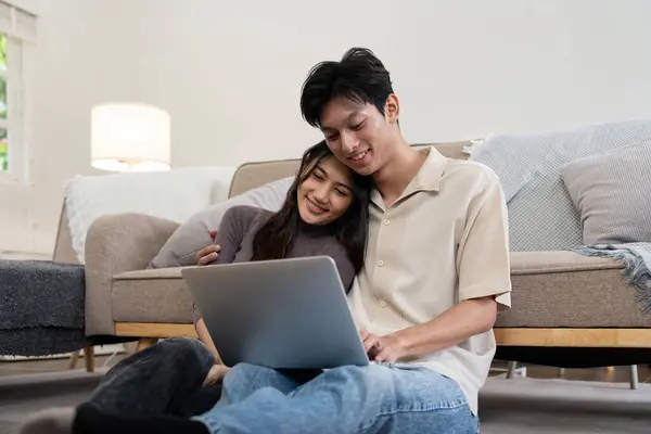 Happy couple asian with laptop on floor in the living room at home.