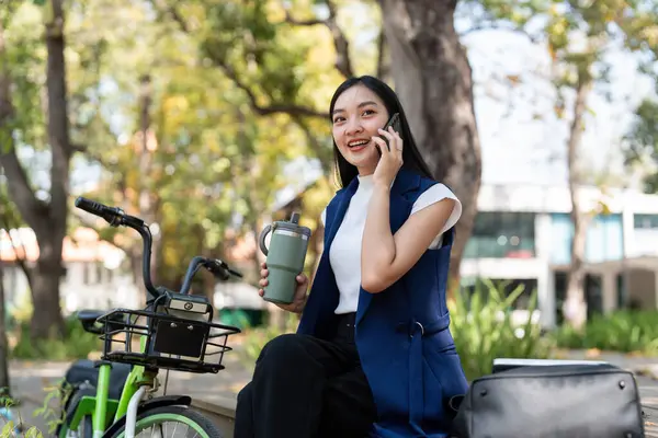 Asiatisk Forretningskvinne Med Sykkel Ved Hjelp Smarttelefon Sitter Utenfor Kontorbygningen – stockfoto