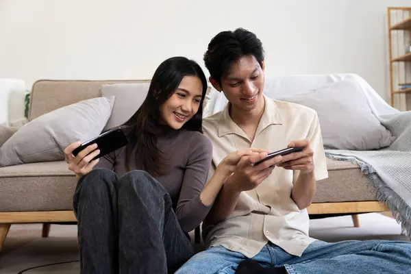 Happy couple asian young women happy enjoy playing match game online game happy relax smile laugh joy fun video gaming app. on couch in living room at home.