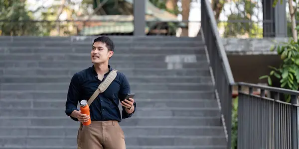 笑顔のアジアのビジネスマンは街で再利用可能なエコフレンドリーなエコカップを保持しながら働くために歩きます — ストック写真