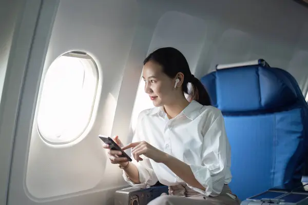 Uma Mulher Está Sentada Num Avião Com Telemóvel Mão Ela — Fotografia de Stock