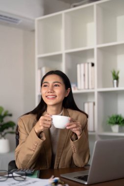 Evden çalışıyorum. İş kadını odada dizüstü bilgisayar kullanıyor. Çevre dostu iş kadını sabah kahve içmek için masa başında çalışıyor, serbest, yeşil oda alanı, sürdürülebilir yaşam tarzı konsepti.