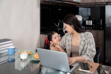 Çalışan anne ev ofisinden çalışıyor. İş kadını ve şirin çocuk dizüstü bilgisayar kullanıyor. Evde serbest çalışıyor. Hayat tarzı aile hayatı yaşıyor..