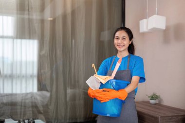 Temizlik ürünleri, ve evde bakterileri temizlemek için yatak odasında Asyalı kadın temizlik sepetleri. Oda temizleyici ya da konteynırlı hizmetçi..