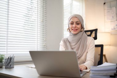Başörtüsü takmış Asyalı Müslüman iş kadını modern ofiste kağıt belgelerle çalışıyor. çeşitlilik ve ofis kavramı.