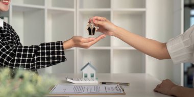 Emlakçı müşterilere ev ve anahtar ve ev sahipliği yapıyor ve ev sigortası sözleşmesi ipotek kredisi konsepti.