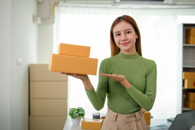 Genç iş kadını Asyalı dükkanında online ecommerce alışverişi yapıyor. Genç bir kadın müşteriye teslim etmek için bir paket ürün satar. Online satış.