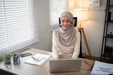 Başörtüsü takmış Asyalı Müslüman iş kadını modern ofiste kağıt belgelerle çalışıyor. çeşitlilik ve ofis kavramı.