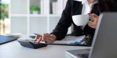 İş kadını muhasebeci ofis odası, iş finans, vergi, muhasebe kavramında mali veri tasarrufu için hesap makinesi ve dizüstü bilgisayar kullanıyor..