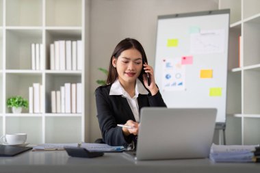 Kendine güvenen iş kadını telefonda konuşuyor. Gülümseyen kadın iş adamı konuşuyor. Ofiste telefonla konuşuyor. Masada oturuyor..