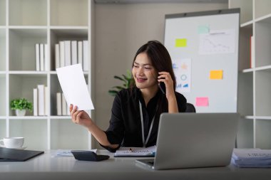 Kendine güvenen iş kadını telefonda konuşuyor. Gülümseyen kadın iş adamı konuşuyor. Ofiste telefonla konuşuyor. Masada oturuyor..