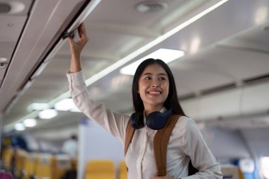 Alone Asian woman passenger traveling by plane. happy traveler on board. Solo travel concept. clipart