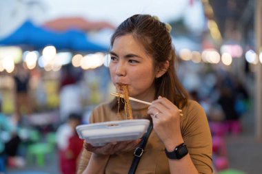 Genç Asyalı turist kadın gezgin Tayland eriştesi yiyor. Geleneksel Chiang Mai Tayland sokak yemekleri...