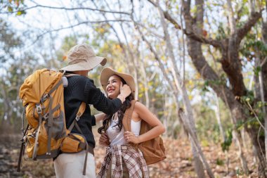 Sırtlarında sırt çantasıyla neşeli, romantik lezbiyen çift gezgin yazın dağlarda ormanda yürüyüşe çıkar..