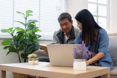 Kanepedeki mutlu Asyalı çift dizüstü bilgisayarla film, eğlence ve yayın izledikleri için. Oturma odasında dinleniyorum...