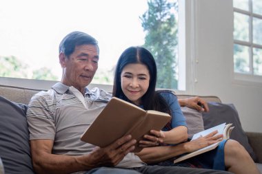 Mutlu yaşlı çift evde tatil tatili için oturma odasında birlikte kitap okuyarak rahatlıyor..