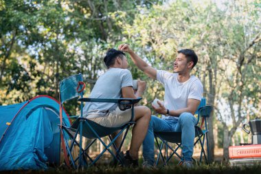 Erkek eşcinsel çift Asyalı çadır kampı ve çeşitli macera yaşam tarzlarıyla aktif yaz tatili için seyahat ediyor. Kahve içip sohbet ediyoruz..