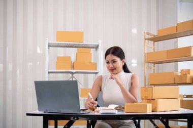 İnternetteki Asyalı kadın, dizüstü bilgisayardaki müşteri adresini ve paket bilgilerini kontrol et. Çevrimiçi alışveriş kavramı.