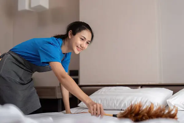 女性アジア人スタッフのクリーニングサービス ツール バケツ 寝室をきれいにするプロダクトが付いている若い女性のクリーナー ベッドから塵 — ストック写真