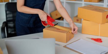 Kadınlar paket kutuları eklemek için koli bandı kullanırlar ve evde paketleme, nakliyat, çevrimiçi satış İnternet pazarlama ekommerce konsepti başlangıç iş fikri için ürünleri hazırlarlar..