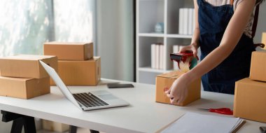 Kadınlar paket kutuları eklemek için koli bandı kullanırlar ve evde paketleme, nakliyat, çevrimiçi satış İnternet pazarlama ekommerce konsepti başlangıç iş fikri için ürünleri hazırlarlar..