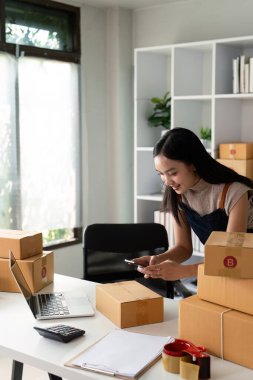 İnternette satmak ve paketlenmiş ürünleri hazırlamak için cep telefonu ya da akıllı telefon dijital kamerasıyla fotoğraf çeken genç kadınlar. Çevrimiçi fikirler satılıyor.
